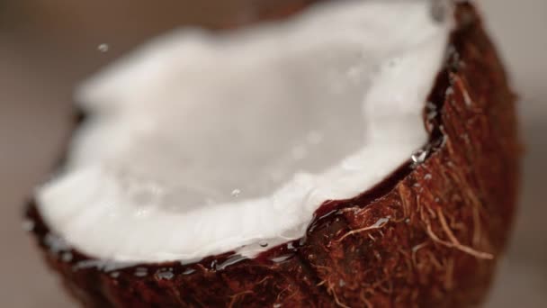 MACRO El jugo de coco salpica sobre el coco con carne prístina y cáscara marrón — Vídeo de stock