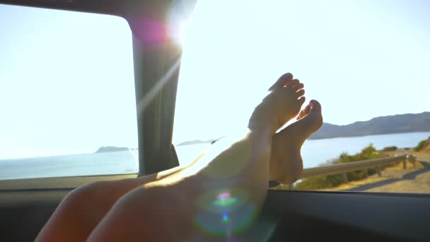 POV: 창문 밖으로 발을 내밀고 차에서 휴식을 취하는 태평 한 여성 관광객. — 비디오