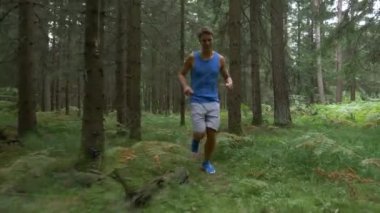 Terli, atletik bir adam cennetlik yeşil ormanda koşuyor..
