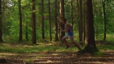 Sporcu, boş bir orman patikası boyunca uzun ve rahatlatıcı bir yürüyüş yapar.