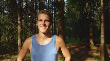Mutlu erkek koşucu ormanda eğlenceli bir koşuyu bitirdikten sonra gülümsüyor.