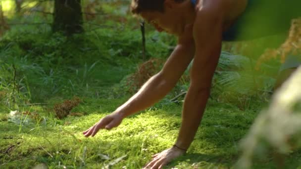 AFSLUITEN: Jonge mannelijke trail runner reizen en valt op de zachte mossige grond. — Stockvideo