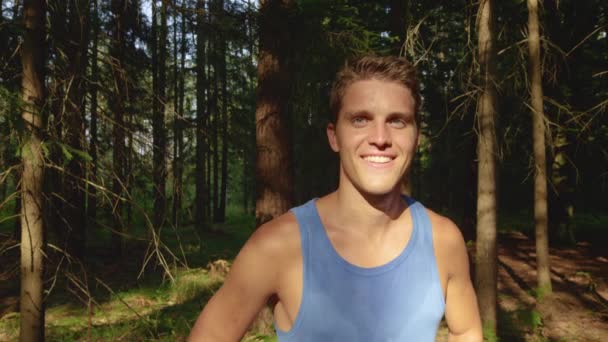 FERMER : L'homme en forme se tient fièrement devant une forêt après avoir fait du jogging dans la nature . — Video