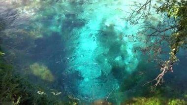 Taze turkuaz renkli su kabarcıkları kuyudan çıkar ve nehri doldurur..