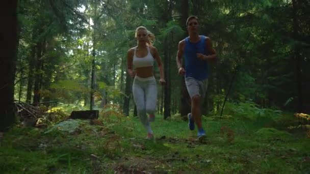 Nah dran: Aktiver Mann geht mit Freundin zum Joggen in den sonnigen Wald. — Stockvideo