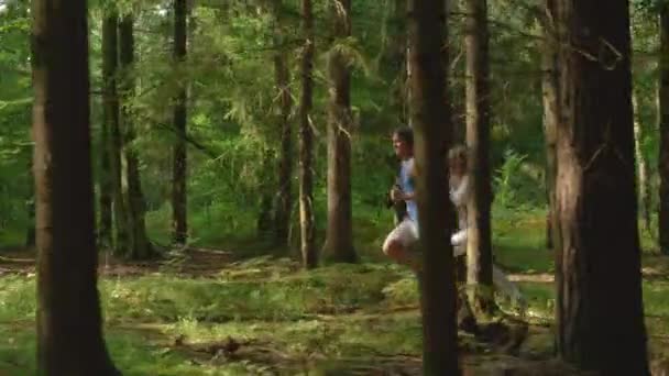 SLOW MOTION: bekymmerslös sportig joggare par utforska den natursköna soliga skogen. — Stockvideo