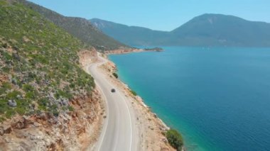 Bir sahil yolundan giderek adayı keşfe çıkan bir arabanın arkasında uçmak..
