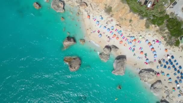 AERIAL: Voando acima de turistas despreocupados relaxando na costa arenosa de Lefkada. — Vídeo de Stock