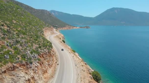 DRONE: Volando detrás de un coche explorando la isla conduciendo por una carretera costera . — Vídeo de stock