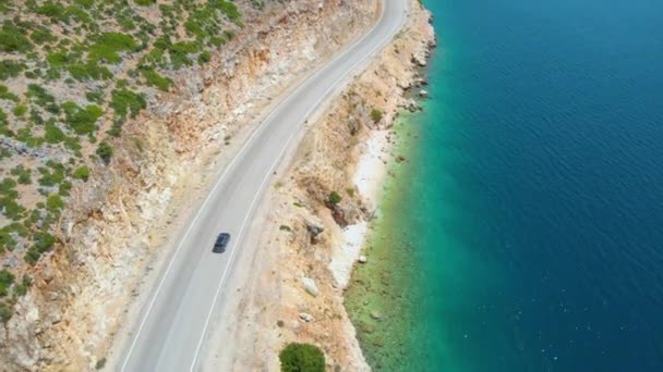 AERIAL: Az emberek cirkáló mentén a lenyűgöző partvonal Lefkada egy szürke autó. — Stock videók