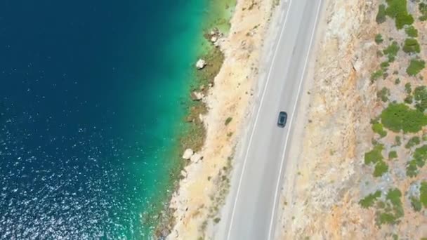 TOP DOWN: Grijze auto rijdt langs de schilderachtige kustweg op een zonnige dag in Lefkas — Stockvideo