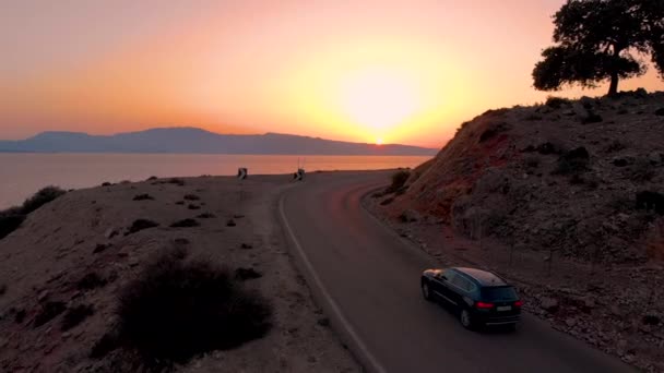 AERIAL: SUV preto conduz até uma estrada sinuosa com uma visão perfeita do oceano calmo — Vídeo de Stock