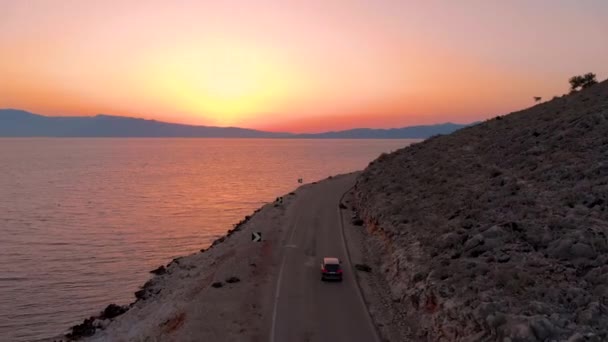 AERIAL: In einem schwarzen SUV bei atemberaubendem Sonnenaufgang Lefkas erkunden. — Stockvideo
