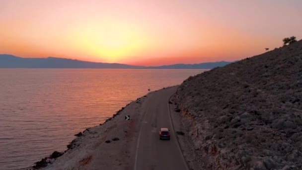 AERIAL: Volando detrás de un SUV negro explorando Lefkas al amanecer impresionante . — Vídeo de stock