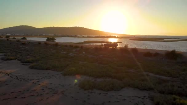 LENS FLARE : Voyageurs en voiture noire sur une route panoramique traversant une baie. — Video