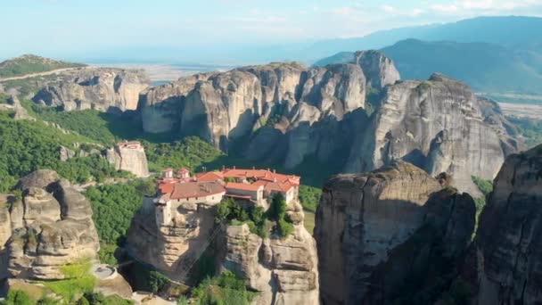 AÉRIAL : De hautes formations rocheuses entourent le village idyllique isolé de Grèce. — Video