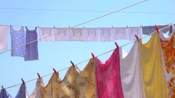 CLOSE UP: Seprei penuh warna, pakaian, dan handuk digantung kering di udara musim panas. — Stok Video