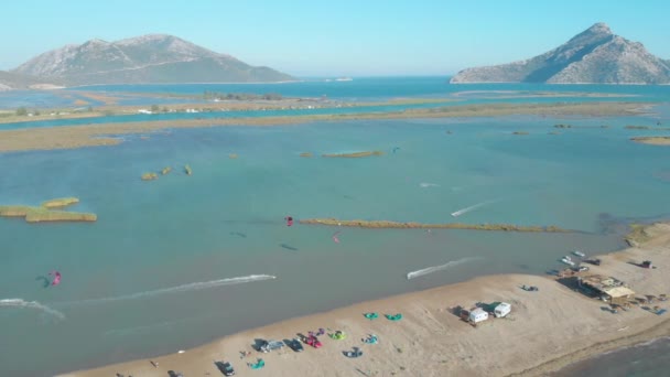 AERIAL: Sportiga turister kiteboarding runt den blåsiga viken i den grekiska havet. — Stockvideo