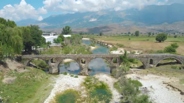 DRONE: Volando sobre el antiguo puente de piedra otomana cruzando el río seco . — Vídeo de stock