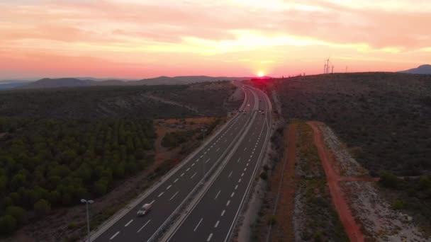 DRONE: Malownicze ujęcie zachodu słońca na autostradzie przejeżdżającej przez kraj. — Wideo stockowe