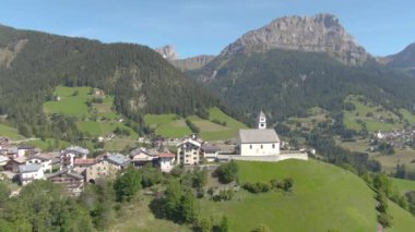 Çevresi İtalyan Dolomitlerle çevrili yeşil bir tepenin üstünde küçük bir köy..
