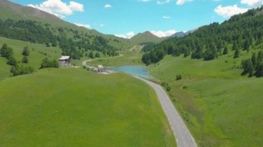 Motosikletli turistler göle doğru manzaralı yoldan gidiyorlar..