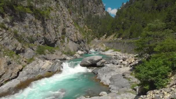 DRONE: Volando lungo le bellissime rapide di smeraldo che corrono lungo la strada di montagna — Video Stock