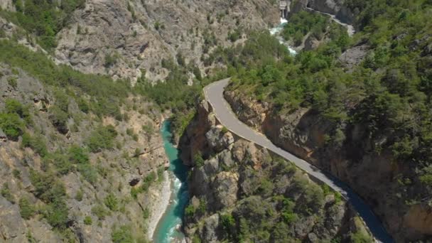 AERIAL: Toeristische auto cruises langs de schilderachtige bergweg die loopt boven een rivier — Stockvideo