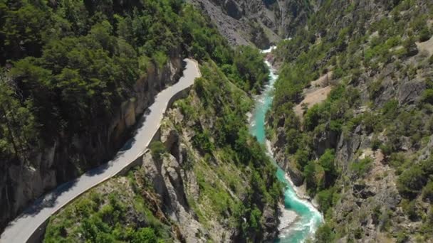 DRONE: Vliegen boven een lege asfaltweg die leidt naar een tunnel boven de rivier — Stockvideo