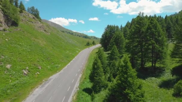 AERIAL:フランスアルプスの山道に沿ってオートバイのライダーと車のドライブ. — ストック動画