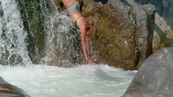 MOCIÓN LENTA: La chica se sumerge primero en un estanque bajo la cascada de cristal . — Vídeos de Stock