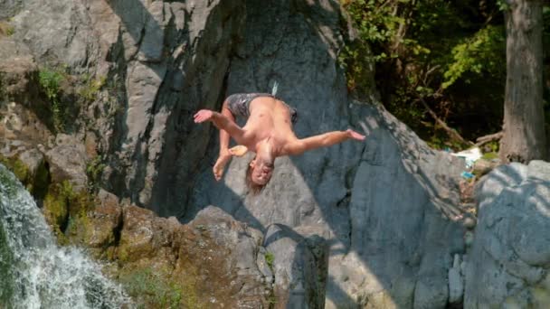 スローモーション:滝から裏返しをする運動選手の息をのむショット — ストック動画