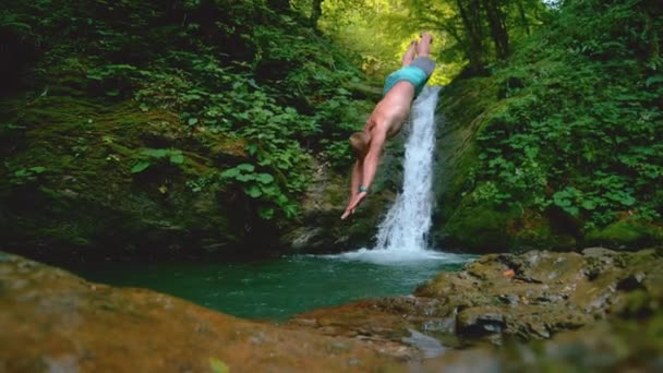 LOW MOTION: Jovem salta para a água corrente refrescante no dia quente de verão . — Vídeo de Stock