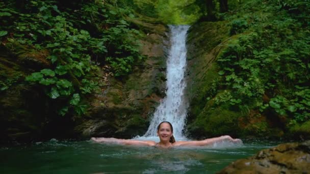 ZAMKNIJ SIĘ: Szczęśliwa dziewczyna chlapie orzeźwiającą wodą podczas pływania w stawie. — Wideo stockowe