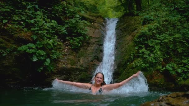 SLOW MOTION: Donna spensierata che si diverte a nuotare e spruzzare l'acqua vetrosa . — Video Stock