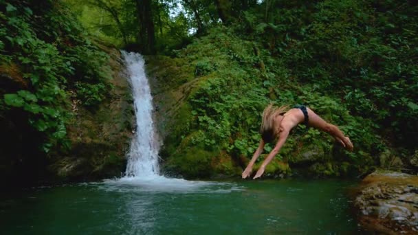 スローモーション:エネルギッシュな女性は、最初にさわやかなエメラルドの水に頭をダイブ. — ストック動画