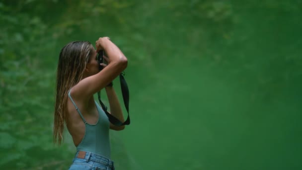 LOSE UP: Ung kvinnlig fotograf med vått hår tar bilder av naturen. — Stockvideo