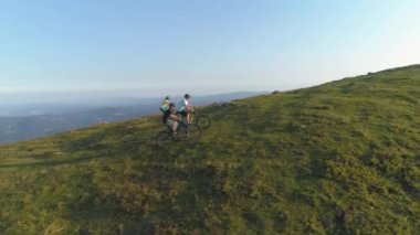 Güneşli bir öğleden sonra çimenli bir tepede bisikletle pedal çeviren arkadaşlar..