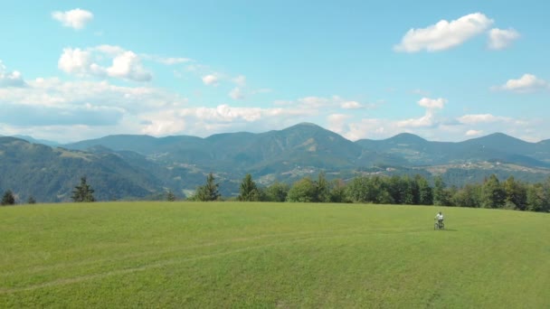 DRONE: Downhill biker pedalling an electric bicycle across a grassy meadow. — Stock Video