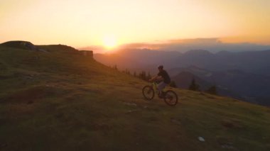 Altın gün batımı, tepeye doğru pedal çeviren dağ bisikletçilerinin yolunu aydınlatıyor..