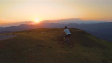 DRONE: Dağlarda elektrikli bisiklet süren aktif erkek turistin arkasında uçmak.