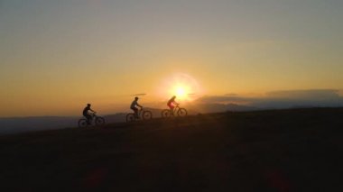 Bisiklet süren turistlerin üzerinde nefes kesici güneş ışınları parlıyor.