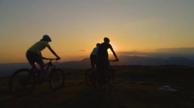 Dağ motorcuları güneş doğarken çimenli tepenin sonuna ve beşlik çakarken