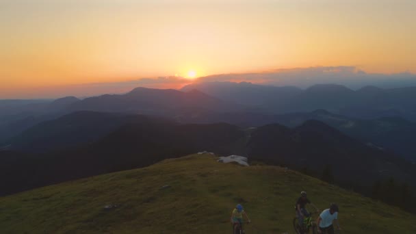 AERIAL: Przyjaciele na rowerze górskim przygoda pedałowania w górę o zachodzie słońca — Wideo stockowe