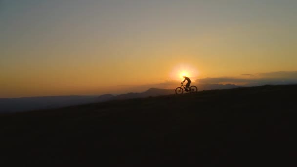 沉默：难以辨认的人在日落时骑着山地车下山. — 图库视频影像