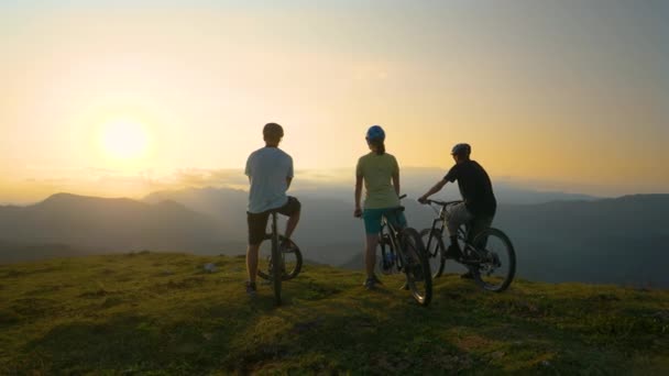 LENS FLARE: Onherkenbare sportieve toeristen rusten op fietsen en observeren zonsopgang — Stockvideo