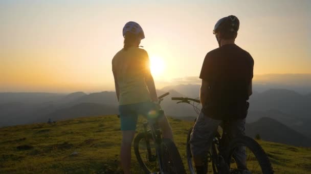 Sluiten omhoog: Gelukkig man en vrouw high five over de zonsondergang na mountainbiken. — Stockvideo