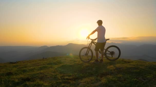 LENS FLARE: L'uomo si riposa dopo una gita in bicicletta e osserva il paesaggio serale . — Video Stock