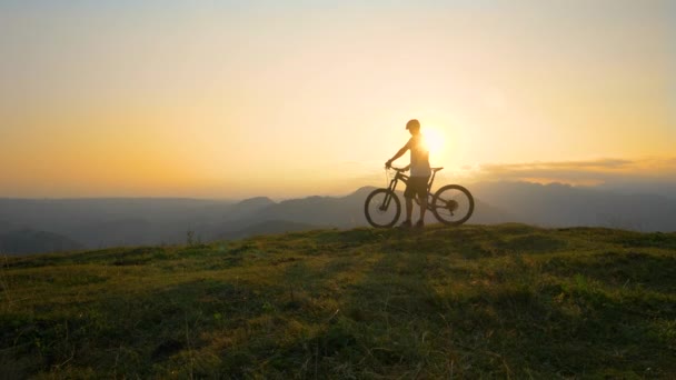 COPIA ESPACIO Rayos de sol dorados brillan en el ciclista de montaña de pie en la cima de una colina — Vídeos de Stock