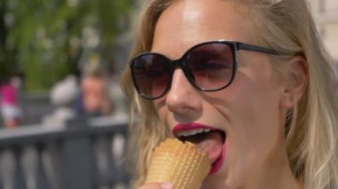 Güneş gözlüklü kız sıcak bir yaz gününde lezzetli dondurmalar yiyor..